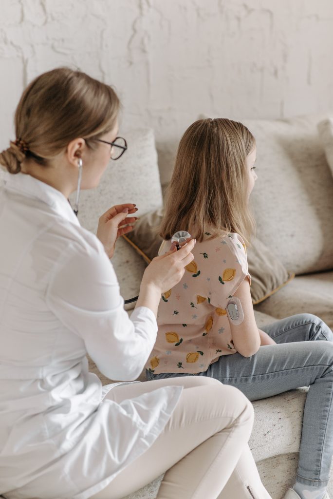 Doctor conducting a health check on a young girl managing diabetes at home.